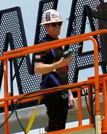 Reigning Verizon IndyCar Series champion Scott Dixon helps install the final two letters over the new Gate 1 Entry Plaza May 11 at Indianapolis Motor Speedway, as part of the $90m Project 100 to enhance the fan experience for the 100th running of the Indy 500, May 29. [FOX 59 screen grab]